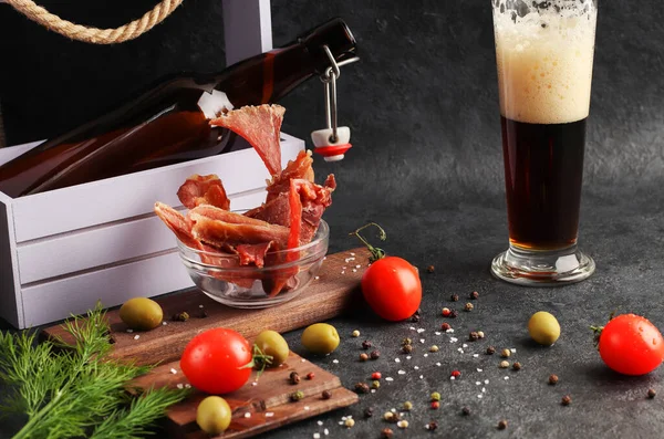 干肉片与香料在玻璃杯在黑暗的背景 调味品 红樱桃西红柿 啤酒的天然点心 有机自制食品 免版税图库照片
