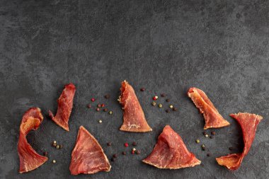 Bira için doğal atıştırmalık. Organik ev yapımı yemekler. Arka planda baharatlı kurutulmuş et parçaları. Baharatlar, kaba tuz, kırmızı kiraz domatesleri, zeytinler. Üst Manzara. Düz yatıyordu. Boşluğu kopyala