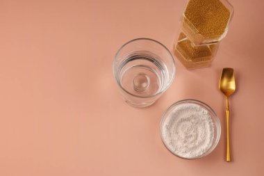 Yenilenme için doğal hidrolize kozmetik kolajen takviyesi. Altın kum saati ve toz kaşığı. Pembe arka planda sağlıklı ve yaşlanma karşıtı rahatlama kavramı. Yukarıdan bak. Boşluğu kopyala.