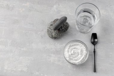 Bir bardak su, arka planda kolajen tozu. Sağlıklı yaşam tarzı kavramı. Cam bardakta hidrolize kolajen ve siyah kaşık. Doğal takviye. Boşluğu kopyala