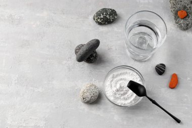 Doğal takviye. Cam bir kasede hidrolize edilmiş deniz kolajeni tozu ve hafif bir zemin üzerinde taşların arasında bir bardak temiz su. Sağlıklı yaşam tarzı kavramı. Boşluğu kopyala