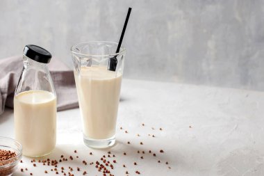 Biberonda süt olmayan organik vejetaryen karabuğday sütü ve beton mutfak masasında bardak. Glüten ve laktozsuz içecek. Boşluğu kopyala