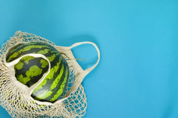 健康食品交付概念 西瓜在一个蓝色背景的绳子袋子里 在可重复使用的生态网中排毒 复制空间 图库图片