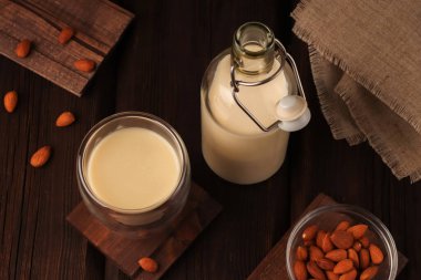 Doğal kahvaltı. Cam bir şişe ve bardakta, glütensiz badem sütü ve ahşap arka planda. Organik vejetaryen içeceği. Kırsal tarzda. Sağlık kavramı