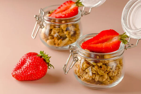Granola healthy food dessert snack. Keeping a healthy breakfast. Muesli with fruits and strawberries on a pink background. Diet concept. Vegetarian food.