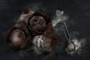 Koyu arkaplanda pudra şekerli ve tarçınlı çikolatalı kek. Üst Manzara. Alçakgönüllülük. Düz yatıyordu.