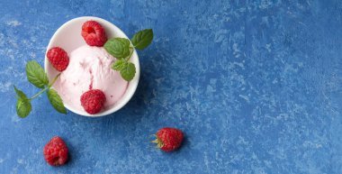 Romantik ve lezzetli bir tatlı. Beyaz bardakta ahududu dondurması ve mavi arka planda bir tutam nane şekeri. Düz yatıyordu. Boşluğu kopyala