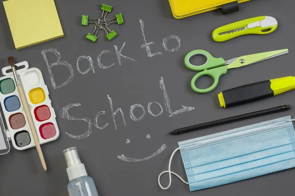 Bright office and school supplies on a dark background. Back to school concept with chalk inscription. Social distance. Hygiene and protection against bacteria and viruses. Stay safe