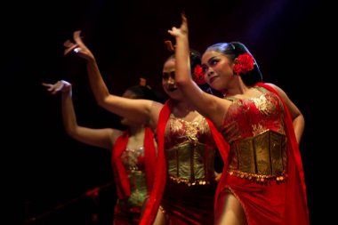 Yogyakarta, Endonezya, 3 Aralık 2025, Kembang Tanjung Kırmızı ve Altın Kostümlü Kadın Dansçılar Grubu Senkronize El Hareketlerini Dramatik Sahnede Gösteriyor