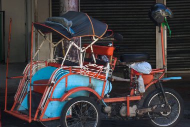Geleneksel Bentor Motorize Rickshaw mavi ve turuncu aksanlı Endonezya Yogyakarta 'da bir caddeye park etmiş, 6 Nisan 2024