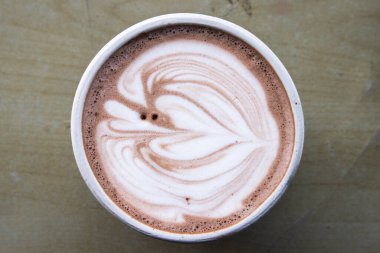 Tahta Masa Yüzeyinde Beyaz Kupada Profesyonel Latte Sanatı ile Gurme Sıcak Çikolatalı Latte, Kafe Menüsü ve Mutfak Tasarımı İçin Kremalı Kakao İçeceği Üst Görünüm Düz Yatağı