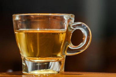 Tahta Masada Sıcak Cam Çay, Zarif Saplı Sıcak Bitki İçeceğinin Profesyonel Yakın Çekimi, Koyu Bulanık Bokeh Arkaplanlı Kafede Gastronomi Mutfak Mutfağı Durgun Yaşamı