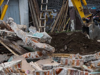 Yıkıma Açığa Çıkan Beton Duvarlı Moloz, Şehir Yenileme için Parçalanmış Tuğla Döküntüsü, Arkaplanda Çalışan Sarı Kazıyıcı Makineli Ev Tahliye Harabeleri