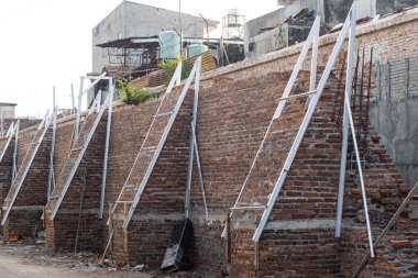 Demir Güçlendirme ve Metal Destek Çerçeveli Büyük Kırmızı Tuğla Duvarı İnşaatı, Profesyonel Korunma Yapısı Endüstriyel İnşaat Alanı, Yüksek Güvenlikli Çevre Geliştirme