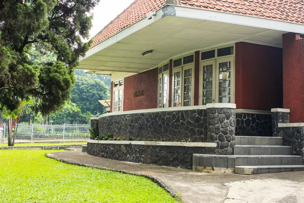 Doğal Taş Duvarlar Terası Kırmızı Dış Duvarı ve Ağaç Gölgesi Altında Yeşil Çimen Bahçesi olan Bir Evin Klasik Mimarisi