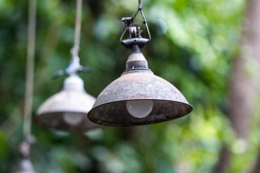 Industrial Rustic Outdoor Pendant Hanging Lamp with Rusty Metal Shade for Cafe Garden and Patio Decor on Blurred Green Foliage Background