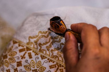 Batik Ağda Süreci için Geleneksel Bakır Canting Aracı, Beyaz Kumaş Yüzeyinde Çiçek Örnekleri ile Otantik Tekstil Sanatı Detaylı Macro