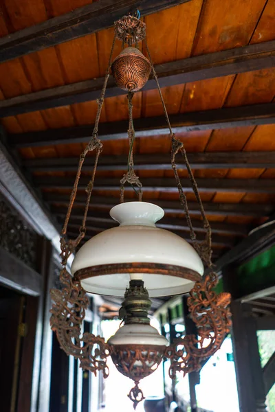 Antique Javanese Hanging Lamp with Ornate Iron Frame and White Glass Shade for Traditional Home Interior Decoration