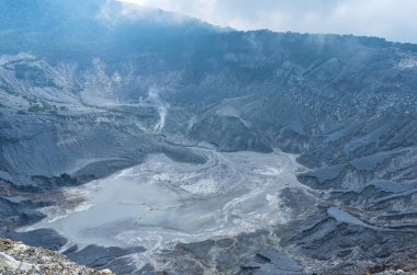 Gri Rocky Cliffs ve Sandy Caldera Zemin Aktif Jeotermal Dağ Manzaralı Büyük Volkanik Krater Bulutlu Gökyüzü Doğal Afet Konsepti Tropikal Dağlık Yabanda