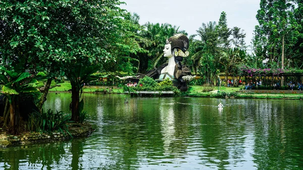Dev Kadın Karakter Heykeli, Tropikal Ağaçlar ve Geleneksel Anıt Yansıması, Açık Hava Rekreasyonu Doğa Arkaplanı ile Park Gölü 'nün Geniş Manzarası