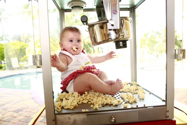 Little girl sitting in popcorn  machine — Stock Photo, Image