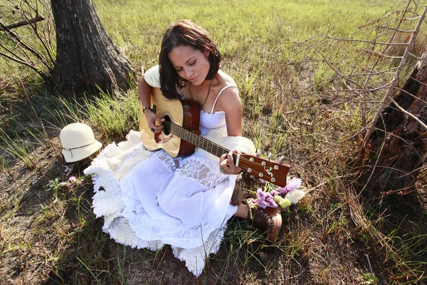 Brunette girl playing guitar in the woods — Stock Photo, Image