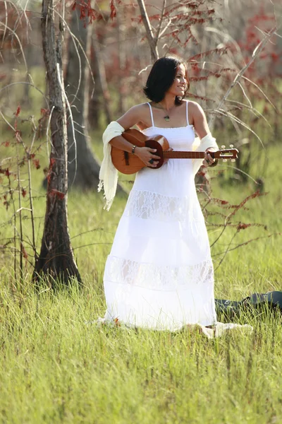 Brunette girl playing guitar in the woods — Stock Photo, Image