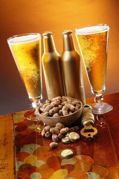 Beer, peanuts, opener and caps — Stock Photo, Image