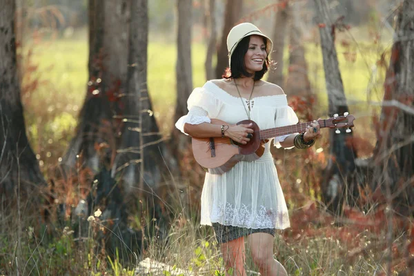 Brunette girl playing guitar in the woods — Stock Photo, Image