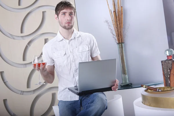 Young man with cognac and laptop — Stok fotoğraf