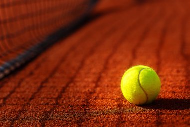 Tenis topu ve antuka arka planlı tenis kortu.