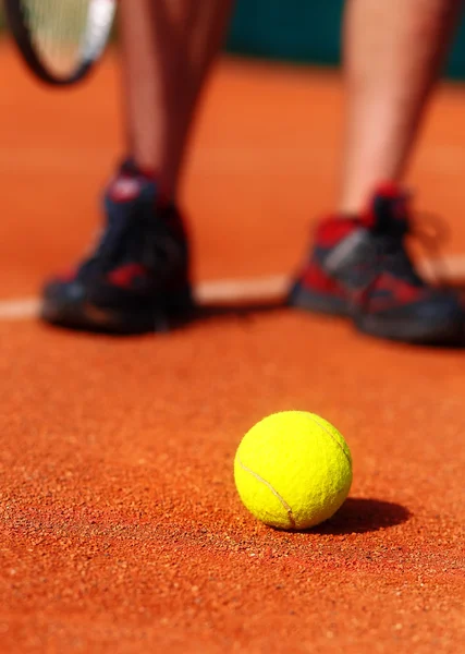 Campo da tennis con palla da tennis e gambe da uomo sullo sfondo . — Foto Stock