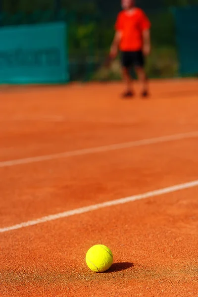 Tennisplatz mit Tennisball und Mann im Hintergrund. — Stockfoto