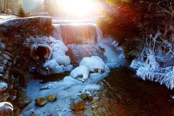 从冰雪覆盖的岩石和太阳的光落下的水冬天场景. — 图库照片