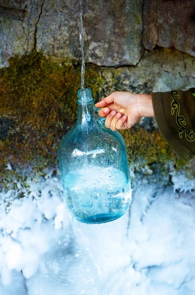 Жінка рука з пляшкою на красивій замерзлій зимовій весні . — стокове фото