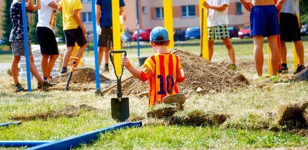 Malý chlapec s kopeček pádlo sledování lidí místo cvičení. Výstavba hřiště. — Stock fotografie
