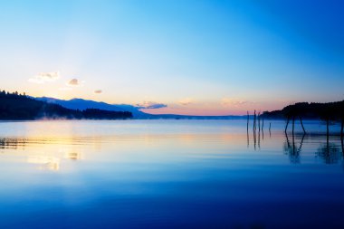 güzel göl manzaralı mistik Dağları ve ağaçları bir köstebek altın kalanlar olarak ile sabah sis içinde mor - mavi tonları.