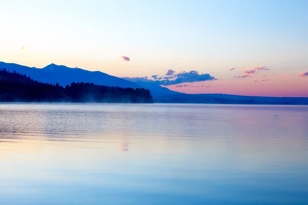 Красивый пейзаж с горами и озером на рассвете в золотых, синих и фиолетовых тонах . — стоковое фото