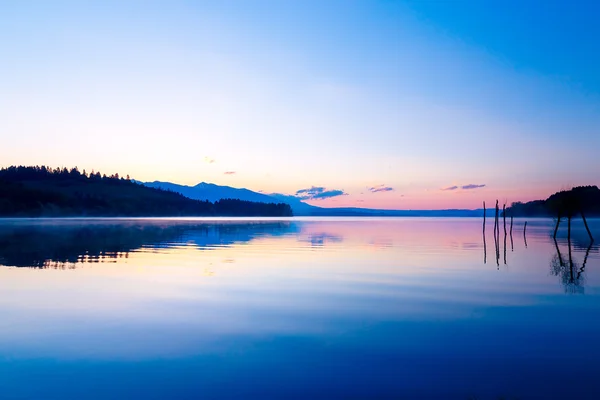 Όμορφο τοπίο με βουνά και τη λίμνη ξημερώματα σε χρυσό, μπλε και μωβ αποχρώσεις. — Φωτογραφία Αρχείου