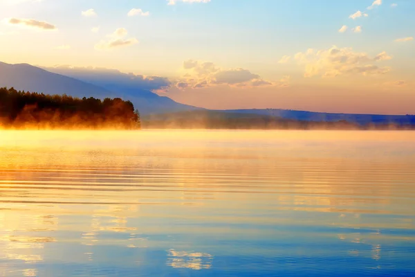 Gyönyörű táj, a hegyek és a tó, arany, kék és narancs tónusokkal hajnalban. — Stock Fotó
