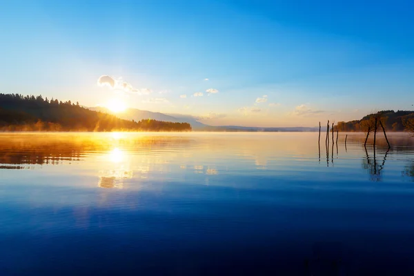 Красивый пейзаж с горами и озером на рассвете в золотых, синих и фиолетовых тонах . — стоковое фото