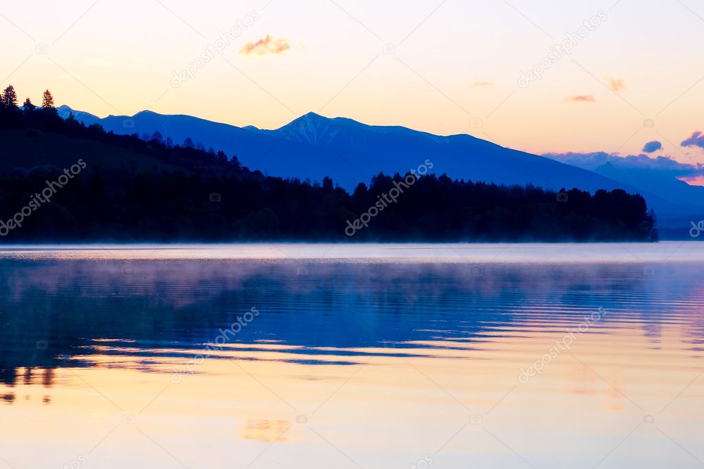 beautiful landscape with mountains and lake at dawn in golden, blue and purple tones. Slovakia, Central Europe, Liptov.