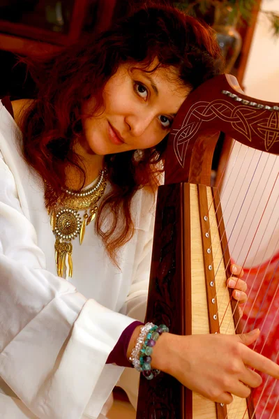 Girl harpist in white dress with jewels playing her instrument. — Stock Photo, Image