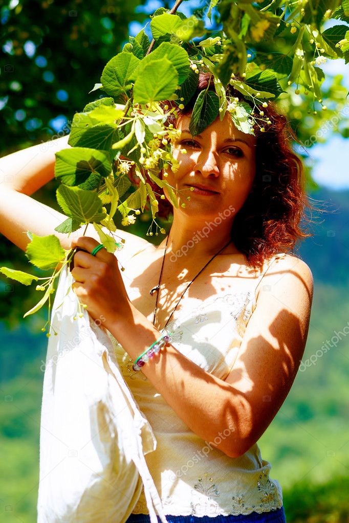 picking up the beautiful linden tree fowers on bright summer day. Eye contact.