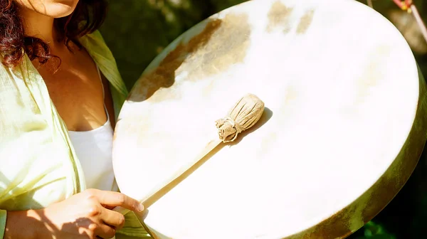 Hermosa chica chamánica jugando en tambor marco chamán en la naturaleza. —  Fotos de Stock