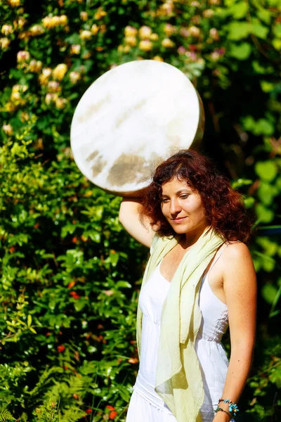 Chica sosteniendo un tambor de marco chamánico en su mano en la naturaleza . —  Fotos de Stock