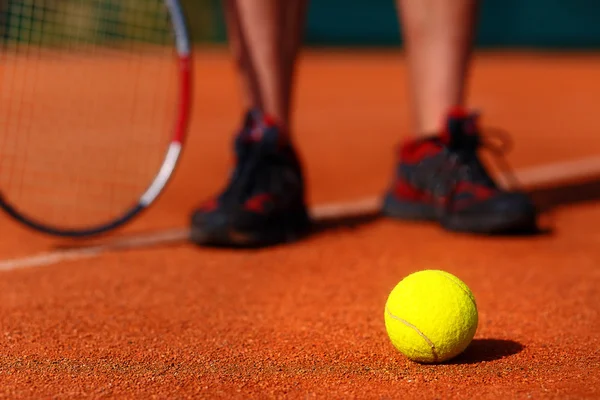 Tennisplatz mit Tennisball und Männerbeinen im Hintergrund. — Stockfoto