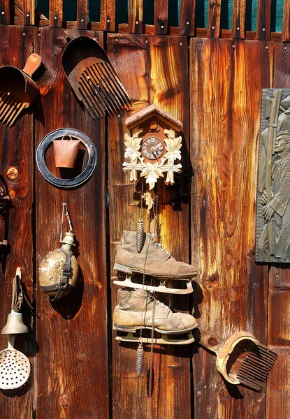 Ancien assemblage d'objets rétro sur un mur en bois. stile rustique. Râteau dans les bleuets, horloge, cloche, art, vieux patins et autres . — Photo