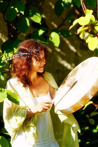 Mooi sjamanistisch meisje spelen op sjamaan frame drum in de natuur. — Stockfoto