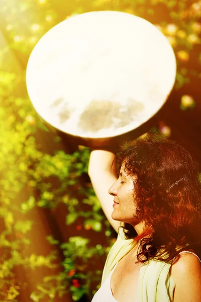 Menina segurando um tambor quadro xamânico em sua mão na natureza. efeito de luz solar . — Fotografia de Stock